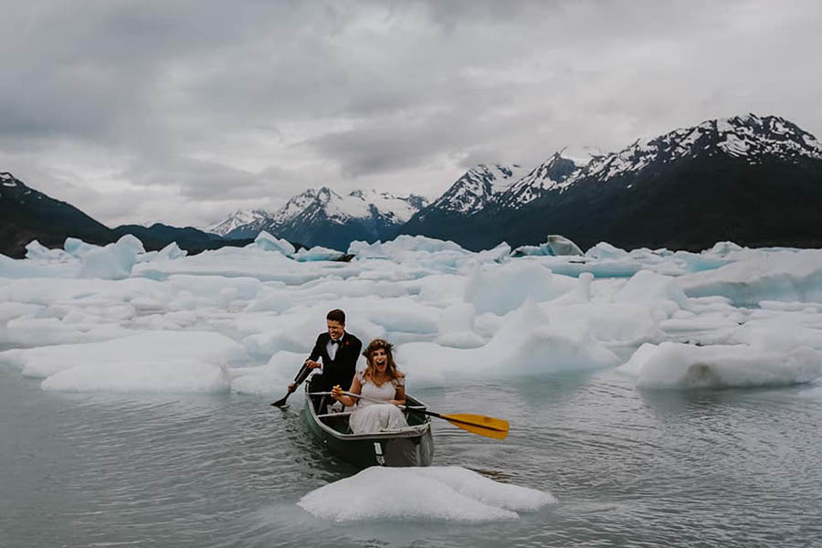 A wedding couple is in a rowboat in front massive ice blocks at the Church State Park in Alaska.