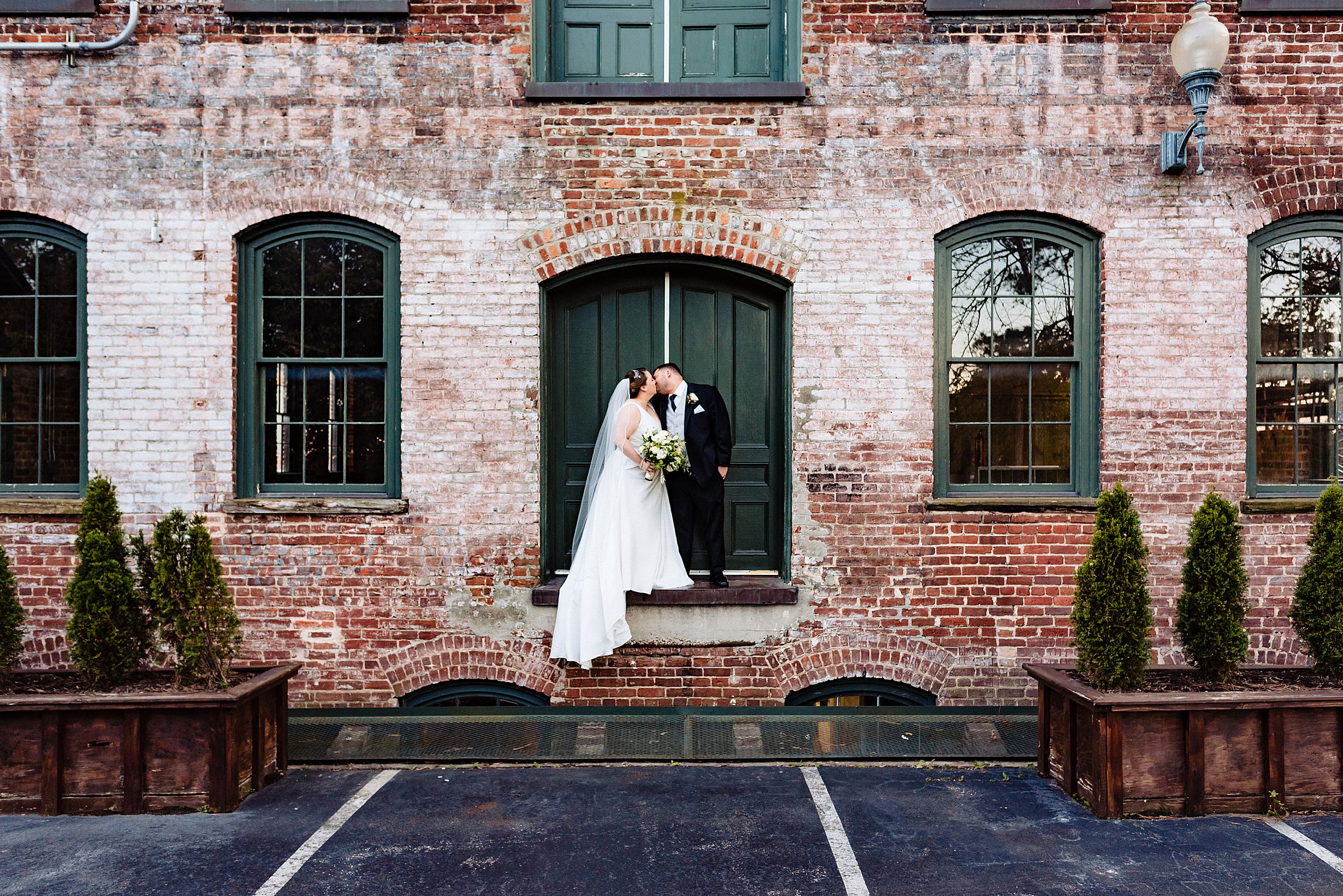 A wedding couple is standing at the Melrose Knitting Mill in Raleigh, NC.