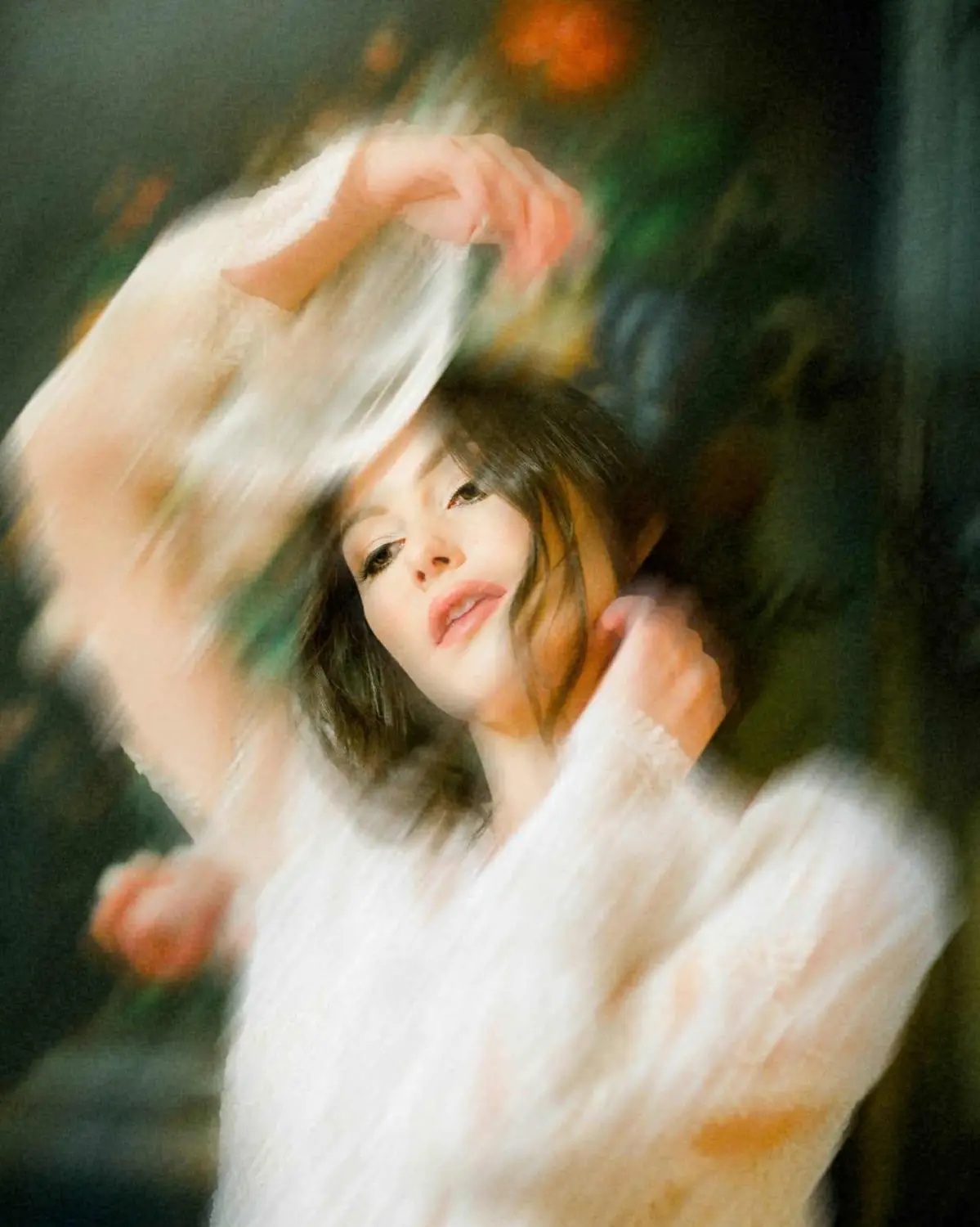 Blurred portrait of a woman in motion: A soft, dreamlike image of a woman with dark hair, captured mid-motion with her arms raised. The movement creates a blurred effect, while her face remains in focus, evoking a sense of fluidity and grace. The vibrant background adds to the ethereal atmosphere.